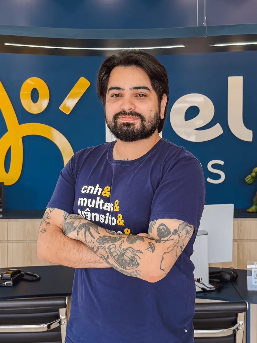 Leonardo, da equipe Help Multas Curitiba Centro, de braços cruzados na recepção da unidade